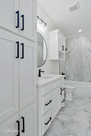 a bathroom with a double vanity sink toilet mirror and bathtub