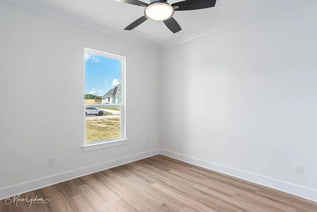 an empty room with windows and fan