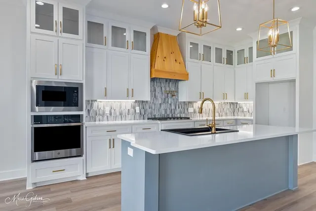 a kitchen with stainless steel appliances granite countertop a sink a stove and kitchen island with wooden floor