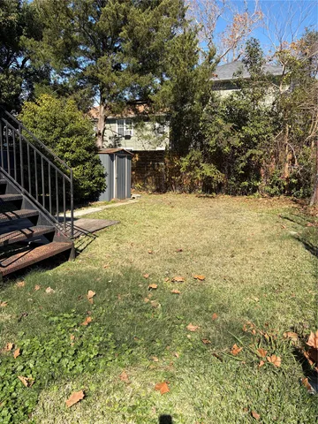a view of a yard with plants and large trees