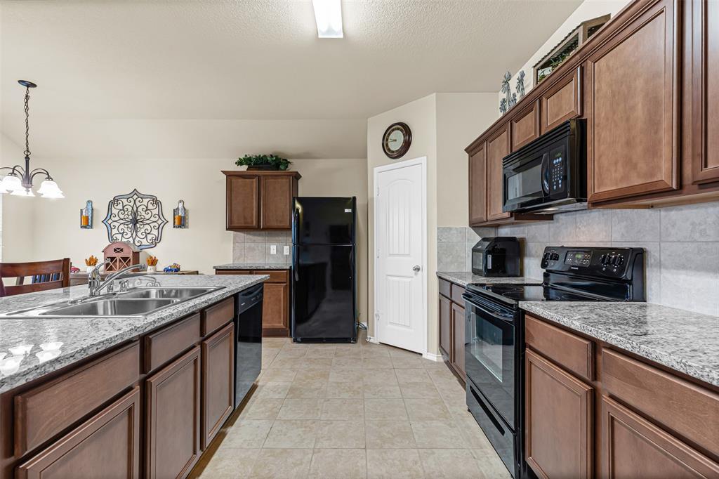 1104 Ruby Court Princeton, TX 75407 - Photo 23 of 40 a kitchen with stainless steel appliances granite countertop a sink stove and refrigerator