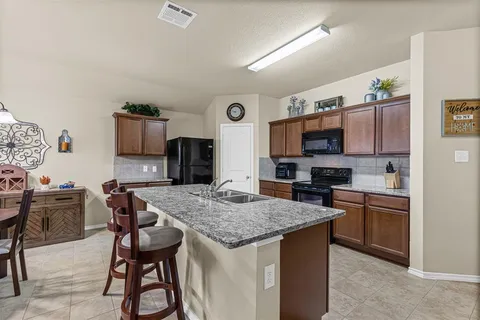 a living room with granite countertop furniture a flat screen tv and kitchen view