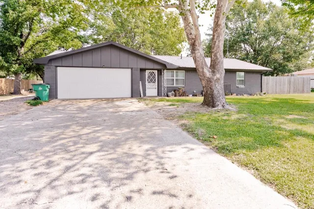 a view of a house with a yard and large tree