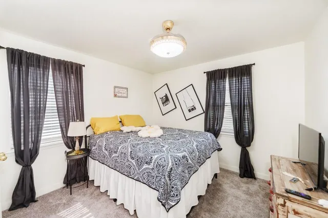 a bedroom with a bed a flat tv screen and dresser