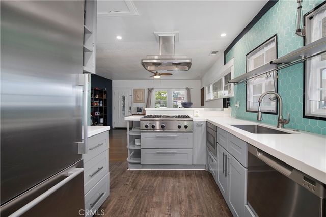 a kitchen with stainless steel appliances a sink cabinets and wooden floor