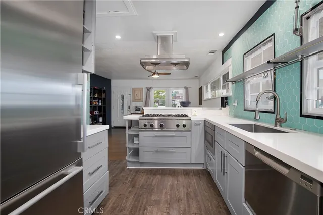 a kitchen with stainless steel appliances a sink cabinets and wooden floor