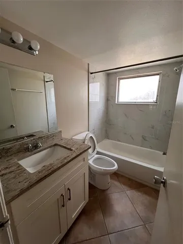 a bathroom with a granite countertop sink a toilet and bathtub