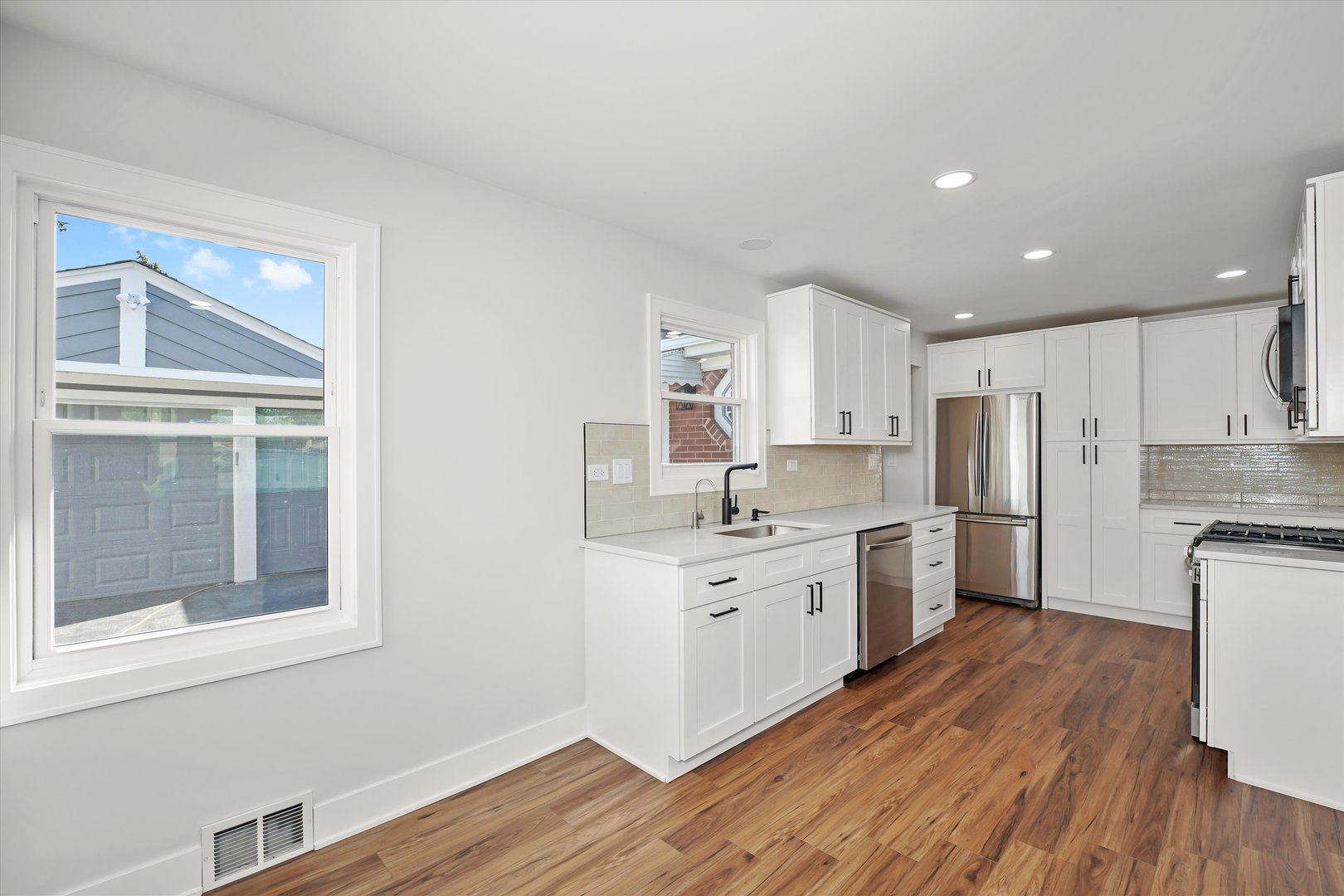 5809 Huron Street Berkeley, IL 60163 - Photo 10 of 26 a kitchen with white cabinets appliances wooden floor and a window