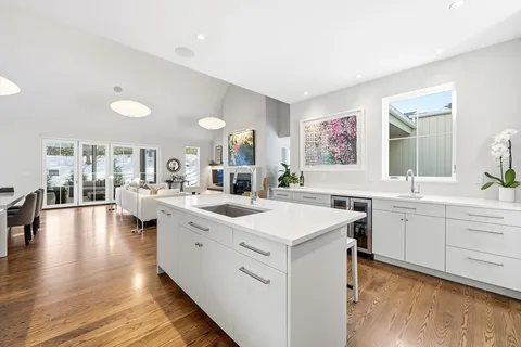 a large white kitchen with center island and stainless steel appliances