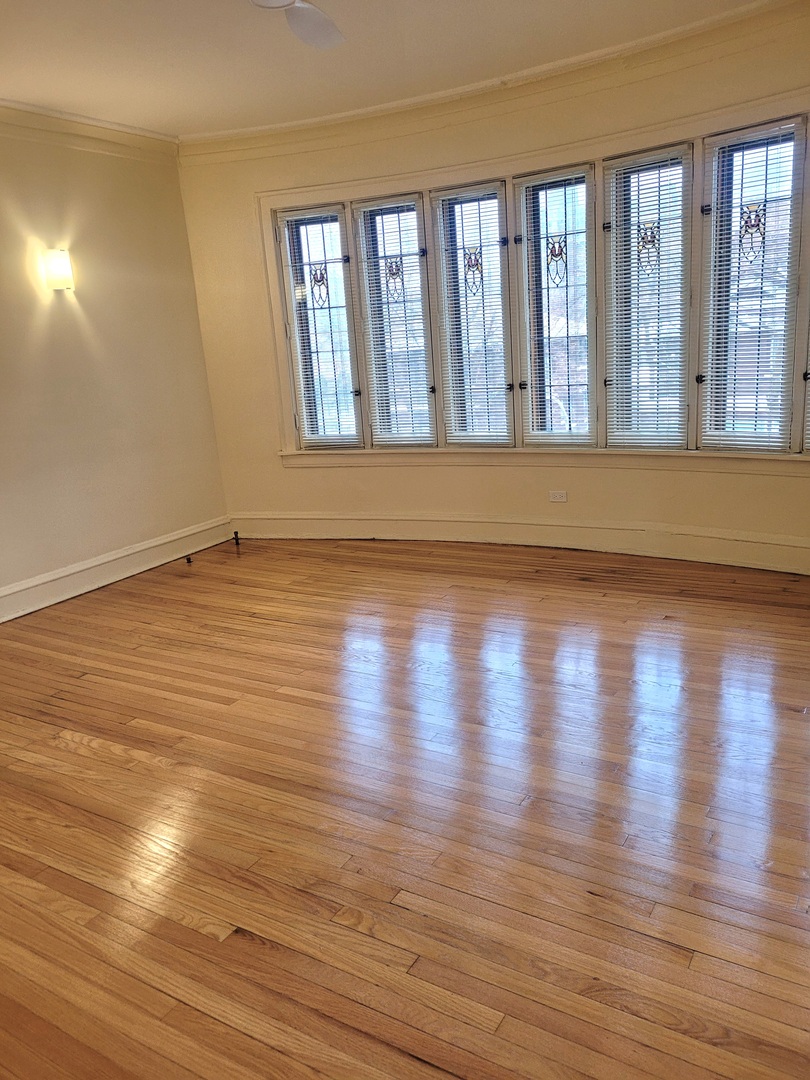 2336 East 68th Street, Unit 2 Chicago, IL 60649 - Photo 6 of 17 a view of an empty room with wooden floor and a window