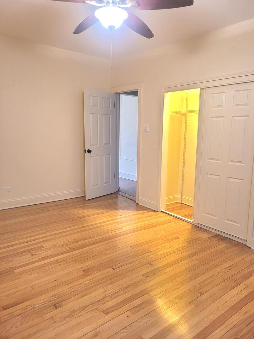 2336 East 68th Street, Unit 2 Chicago, IL 60649 - Photo 8 of 17 an empty room with wooden floor and windows