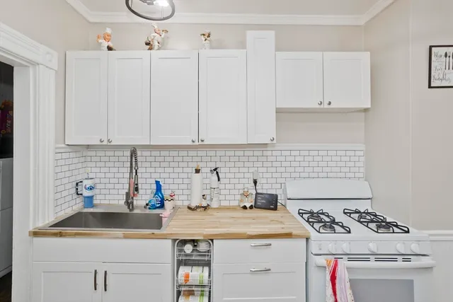 a kitchen with white cabinets sink and stove