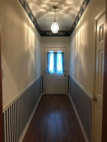 a view of a hallway with wooden floor and a chandelier