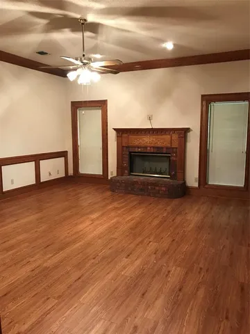 an empty room with wooden floor fireplace and windows