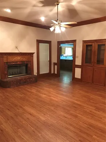 an empty room with wooden floor fireplace and chandelier