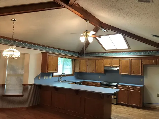 a kitchen with stainless steel appliances granite countertop a sink a stove and a wooden floors