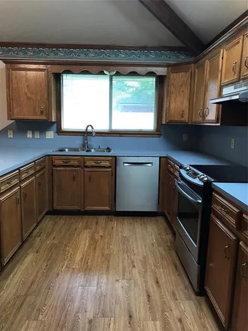 a kitchen with stainless steel appliances granite countertop wooden cabinets and a sink