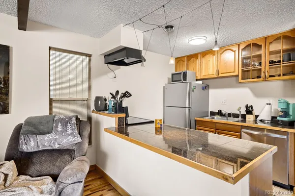 a kitchen with stainless steel appliances granite countertop a sink a stove and a wooden cabinets