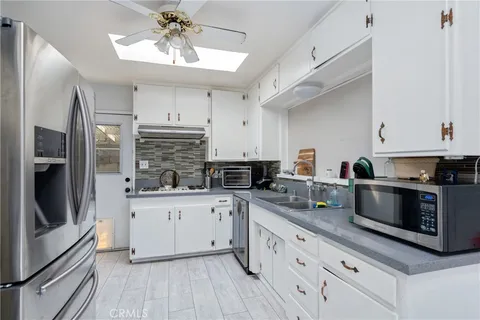 a kitchen with stainless steel appliances white cabinets a sink a stove a refrigerator and cabinets