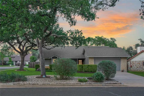 a front view of a house with a garden and trees