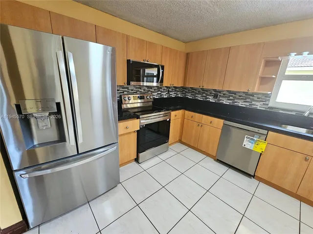 a kitchen with stainless steel appliances a refrigerator sink and microwave