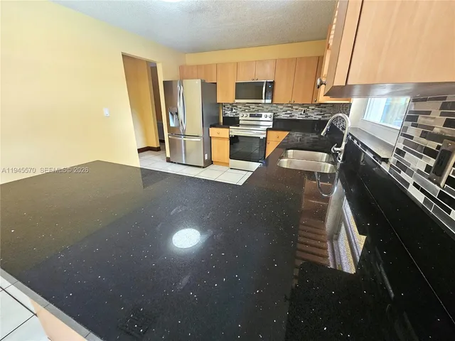 a view of a kitchen with kitchen island stainless steel appliances wooden floor and a window