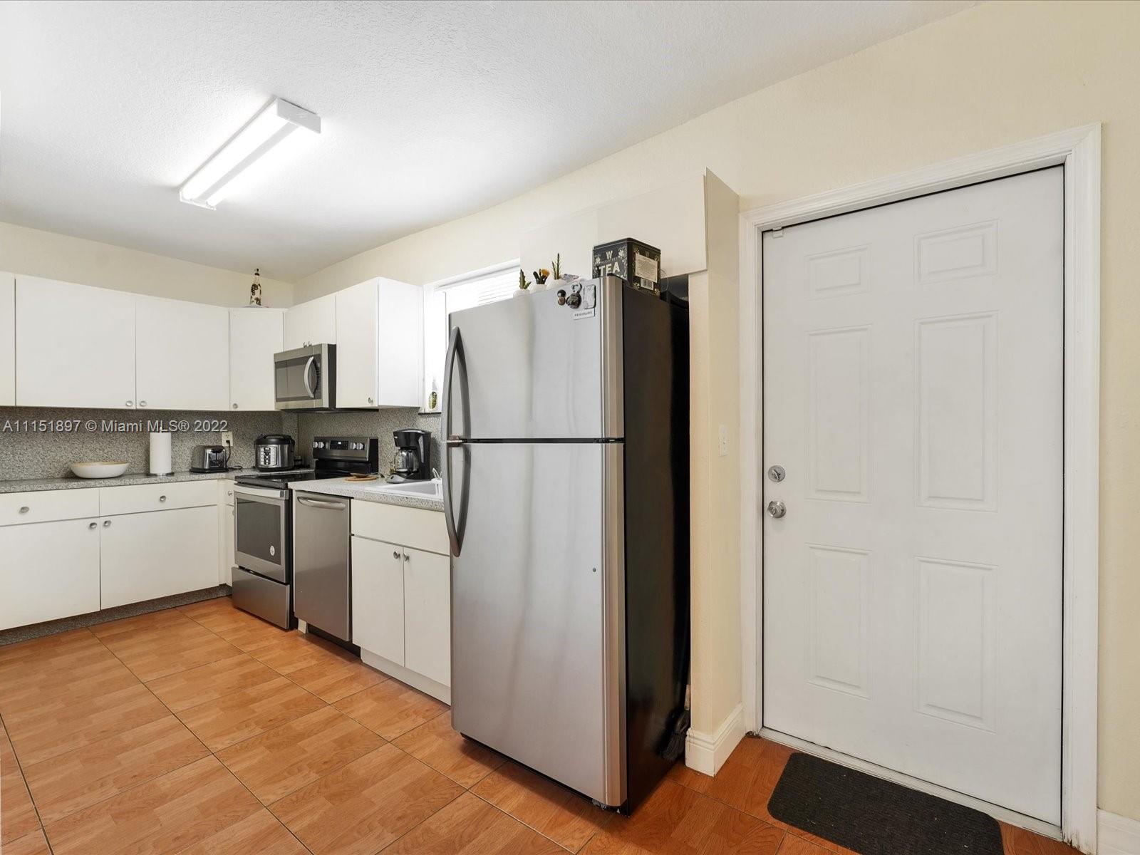 23 Northeast 46th Street Miami, FL 33137 - Photo 11 of 27 a kitchen with a refrigerator and white cabinets