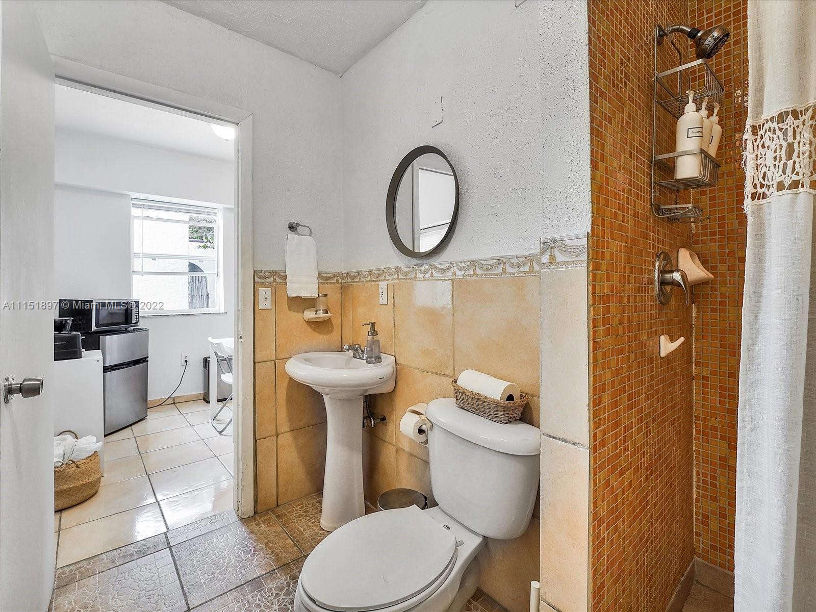 23 Northeast 46th Street Miami, FL 33137 - Photo 24 of 27 a white toilet sitting next to a bathroom sink and a mirror