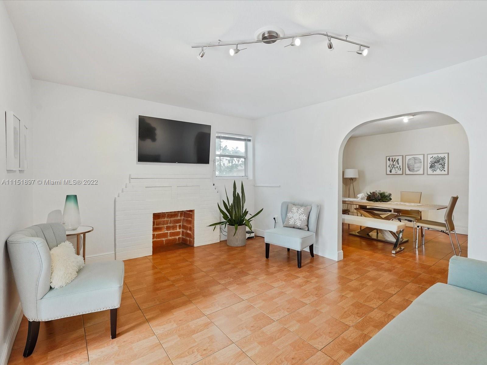 23 Northeast 46th Street Miami, FL 33137 - Photo 4 of 27 a living room with furniture a fireplace and a flat screen tv