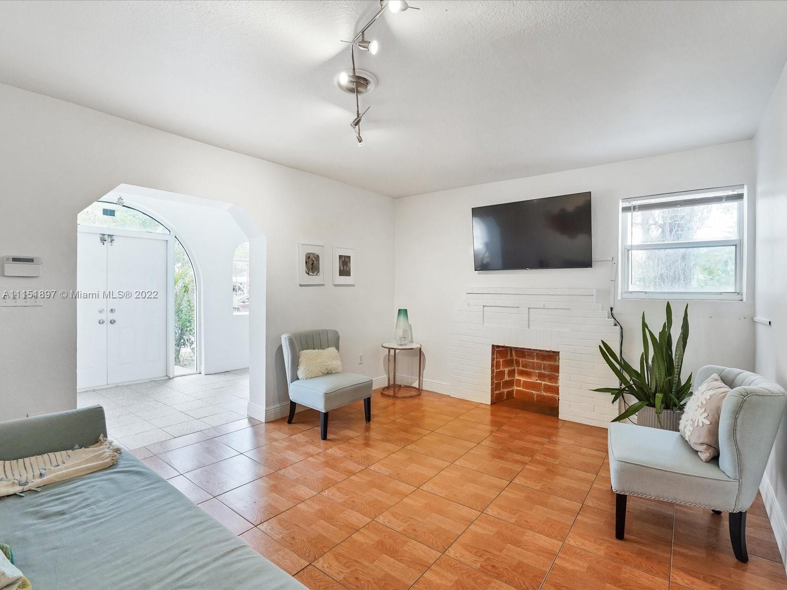 23 Northeast 46th Street Miami, FL 33137 - Photo 5 of 27 a living room with furniture a fireplace and a flat screen tv