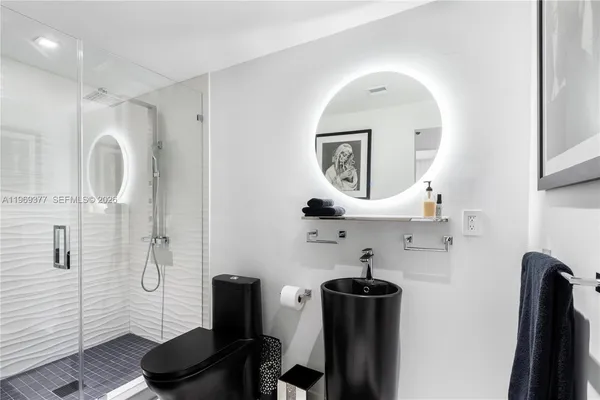 a view of a hallway with wooden floor and a bathroom
