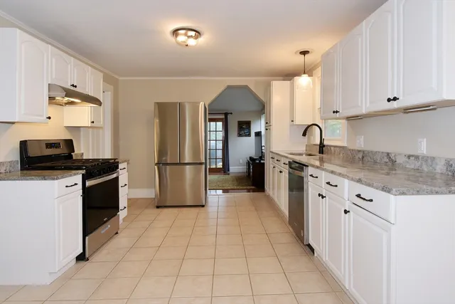 a kitchen with granite countertop a refrigerator stove top oven and sink