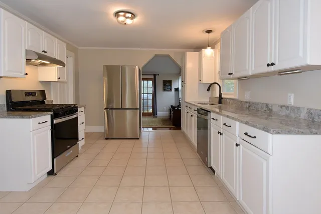 a kitchen with granite countertop a refrigerator stove top oven and sink