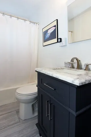 a bathroom with a granite countertop toilet sink and mirror