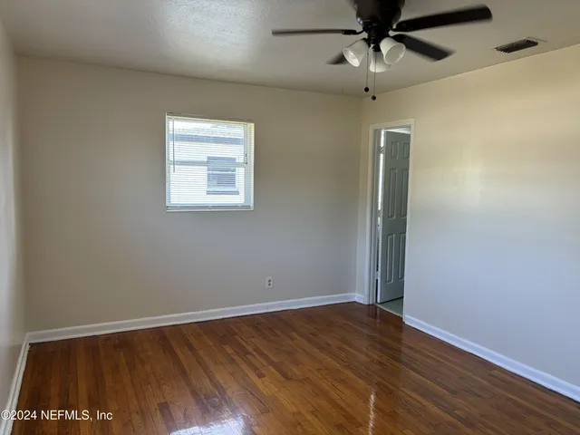 a view of an empty room with wooden floor and a window