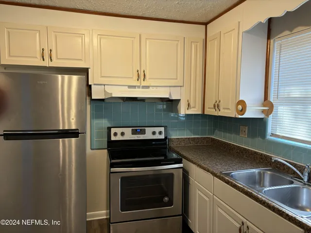 a kitchen with stainless steel appliances granite countertop a refrigerator a sink and white cabinets