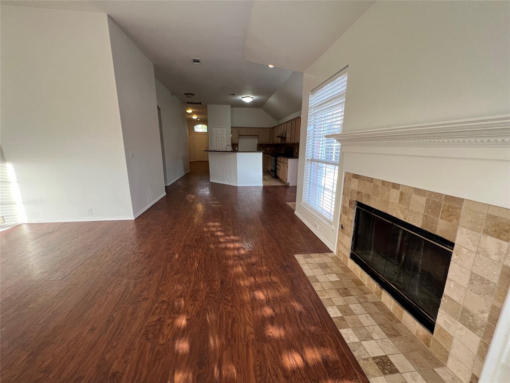334 Touchdown Drive Irving, TX 75063 - Photo 29 of 32 Living area featuring wood-finish flooring, a tiled fireplace with mantel, and a large window with blinds