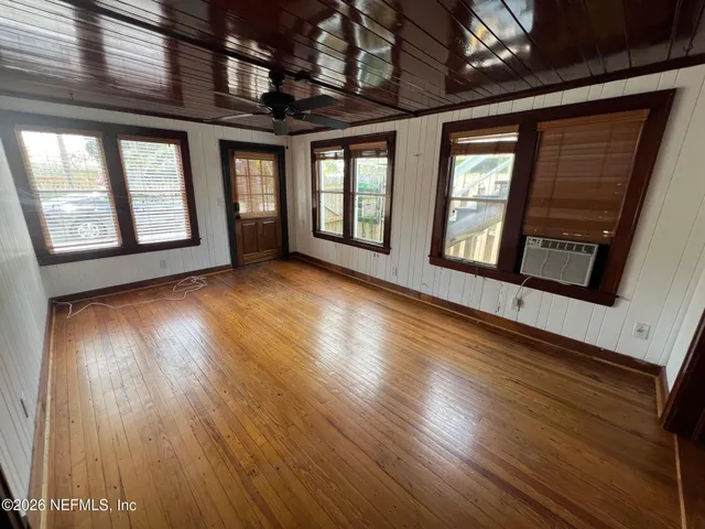 a view of an empty room with wooden floor and windows