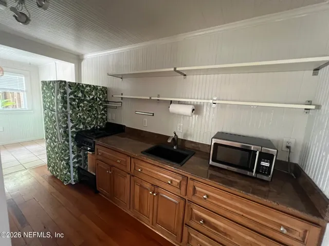 a kitchen with a refrigerator and a wooden floor