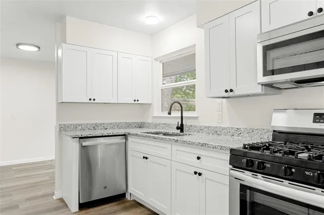 a kitchen with granite countertop white cabinets and appliances