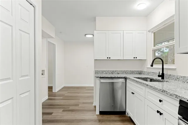 a kitchen with granite countertop white cabinets and a sink
