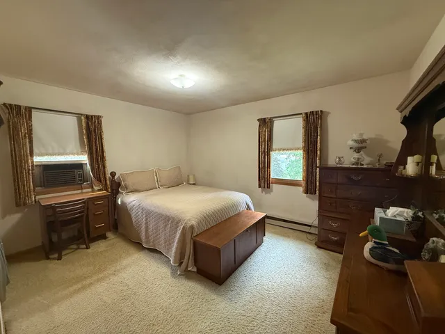 a spacious bedroom with a bed and a dresser next to a window