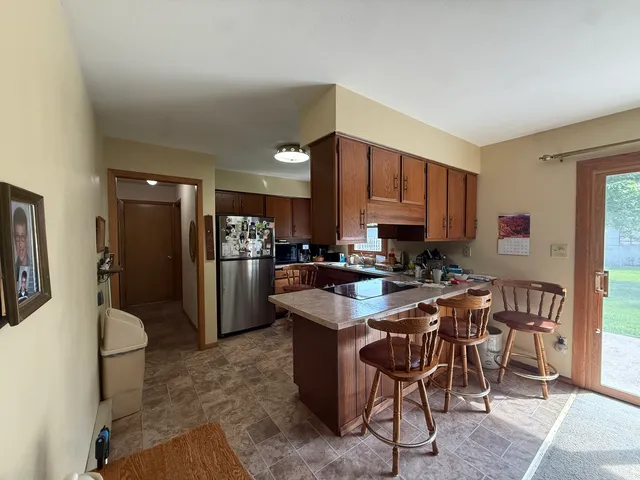 a kitchen with stainless steel appliances granite countertop a table chairs sink refrigerator and cabinets
