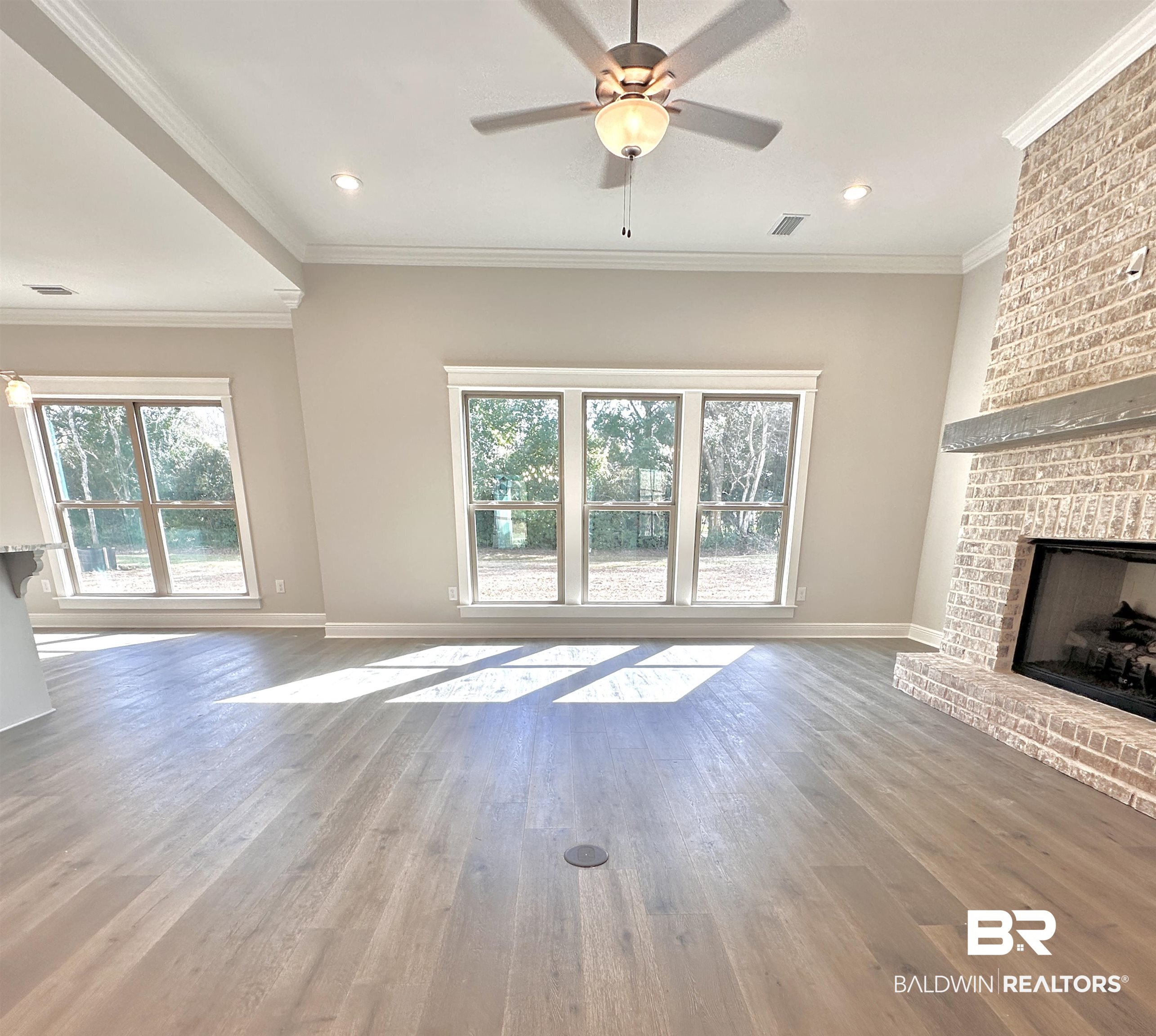 630 Kitfox Avenue Fairhope, AL 36532 - Photo 6 of 40 Unfurnished living room featuring ornamental molding, hardwood / wood-style floors, ceiling fan, and a fireplace