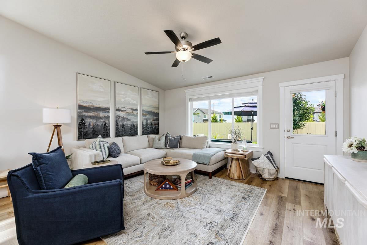 348 West Radiant Rdg Drive Meridian, ID 83642 - Photo 13 of 36 Vaulted ceiling with a ceiling fan, large windows with white trim, wood-finish flooring, and a white exterior door with glass panel