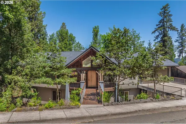 front view of a house with a potted plants and large trees