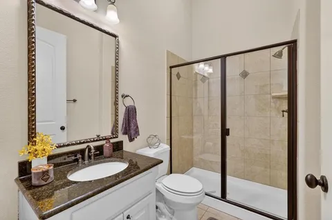a bathroom with a granite countertop sink mirror vanity and toilet