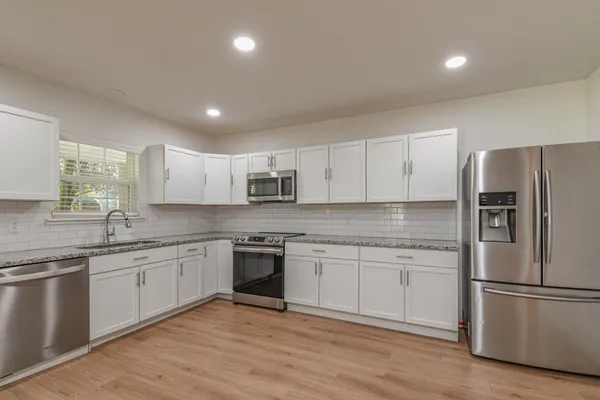 a view of a kitchen with a refrigerator a stove top oven and cabinets