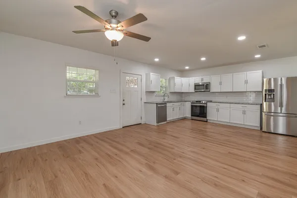 a view of empty room with wooden floor and fan