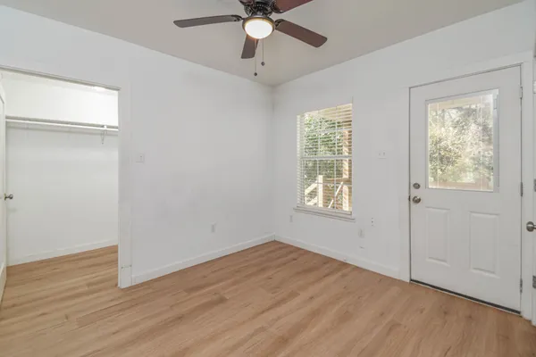 a view of an empty room with wooden floor and window